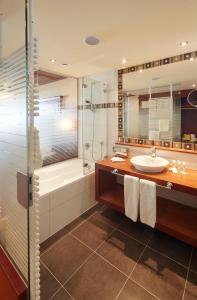 a bathroom with a tub and a sink and a shower at Alpenrose Wellnesshotel in Elbigenalp