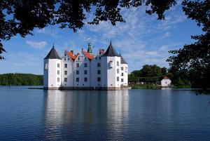 a large white castle sitting on top of a body of water at Hotel Goos in Jübek