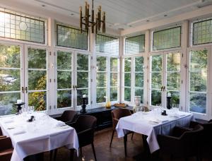 a restaurant with white tables and chairs and large windows at B&B Kasteel Maurick in Vught