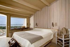 a bedroom with a bed and a chair and a window at Lodge Sainte Helene in Saintes-Maries-de-la-Mer