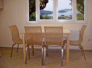 a dining room table with three chairs and two windows at Villas Zoe in Skiathos
