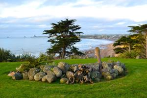 a pile of rocks on the grass near the beach at Ahu Ahu Beach Villas in Oakura