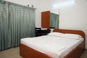 a bedroom with a bed and a table with a chair at Surag Residency in Tiruchirappalli