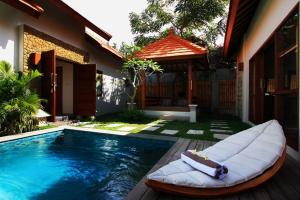 a swimming pool with a bed next to a house at Ananda Private Villa in Gili Trawangan