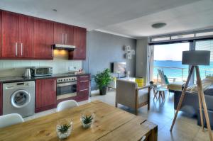 cocina y sala de estar con mesa y comedor en Portico 802, en Bloubergstrand