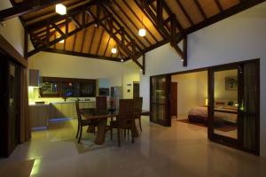 a living room with a dining room table and a kitchen at Ananda Private Villa in Gili Trawangan