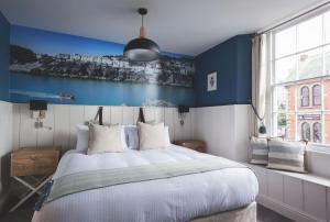 1 dormitorio con 1 cama blanca grande y paredes azules en Havener's, en Fowey
