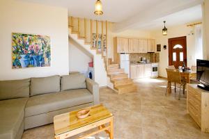 a living room with a couch and a kitchen and stairs at Villas Zoe in Skiathos