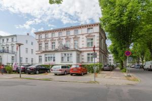 una strada con auto parcheggiate di fronte a un edificio di Haus Troja a Warnemünde