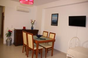 a dining room with a table and chairs and a television at Apartamento Urbanização Aurora Rio in Vila Real de Santo António