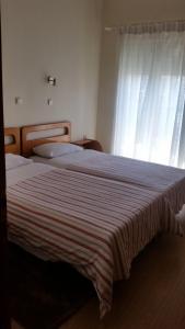 een slaapkamer met een groot bed en een gestreepte deken bij Filareti Hotel in Florina