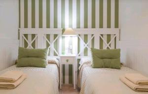 two beds in a room with green and white stripes at Apartamento Alfileritos XX in Toledo