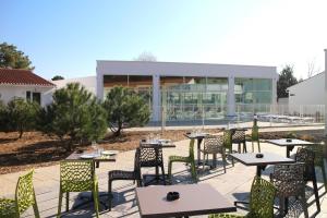 a patio with tables and chairs in front of a building at Vent d'Eden Park Hôtel in Saint-Hilaire-de-Riez