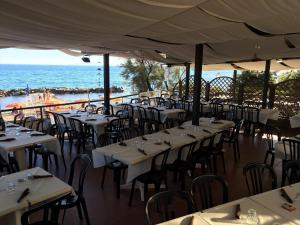 ピオンビーノにあるBaia Toscanaの白いテーブルと椅子が備わる海の景色を望むレストラン