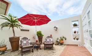 a patio with two chairs and a red umbrella at Meike's Guesthouse in Swakopmund