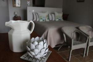 a vase and a bowl on a table with a bed at Tayside Guest House in Kiddʼs Beach
