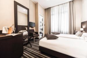 una camera d'albergo con due letti e uno specchio di Hotel Principe Di Torino a Torino