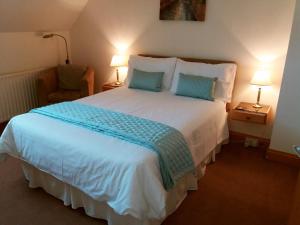 a bedroom with a large white bed and a chair at Osnok in Tenby
