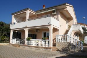 a large white house with a balcony on a street at Apartment Nevenka in Krk