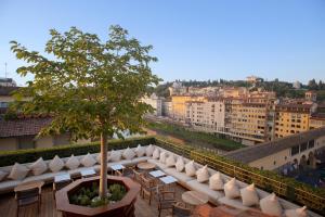 uma varanda com cadeiras e uma árvore num edifício em Hotel Continentale - Lungarno Collection em Florença