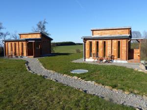a large wooden cabin in a field next to a grass field at Chalets am National Park Eifel in Schleiden