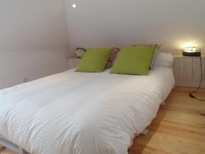 a white bed with green pillows on top of it at AlfamaSweethome 1 in Lisbon