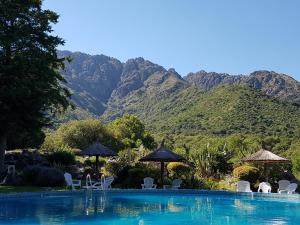 a swimming pool with chairs and umbrellas and mountains at Hostal La Quebrada in Cortaderas