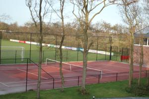 a tennis court with several people playing tennis at Hotel Bloemfontein in Borkum
