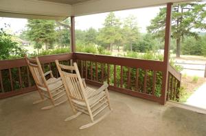 two rocking chairs sitting on a porch with a view at Carolina Landing Camping Resort Cabin 14 in Fair Play