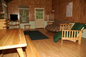 sala de estar con sofá, mesa y TV en Carolina Landing Camping Resort Deluxe Cabin 6, en Fair Play