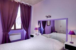 Dormitorio púrpura con cama grande y espejo en Logis Hôtel Le Bocage en Montmarault