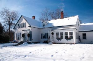 a white house with snow on the ground at Candlebay Inn in Freeport