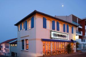 een gebouw met tafels en stoelen ervoor bij Logis Hotel de France in Mimizan-Plage