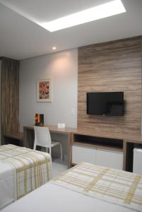 a hotel room with two beds and a desk with a television at Etiqueta Hotel in Santa Cruz do Capibaribe