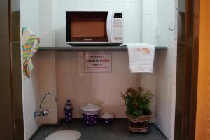 a small bathroom with a microwave and a sink at Pousada Rozam in Olímpia