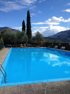 una grande piscina blu con montagne sullo sfondo di Residence Cascata Varone a Riva del Garda