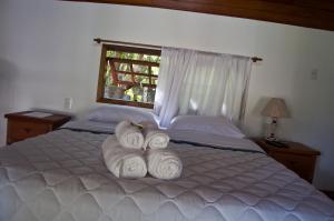 a bedroom with a bed with two rolled towels at Pousada da Neneza in Santa Cruz de Minas