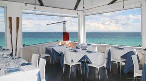 a restaurant with white tables and chairs and the ocean at I Sottani in Monopoli