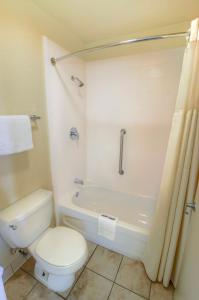 a bathroom with a toilet and a bath tub with a shower at Inn of America in Palm Beach Gardens