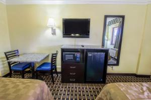 ein Hotelzimmer mit einem Tisch, einem TV, einem Tisch und einem Spiegel in der Unterkunft Inn of America in Palm Beach Gardens