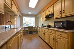 a kitchen with wooden cabinets and a sink and a microwave at Best Western The Inn & Suites Pacific Grove in Pacific Grove