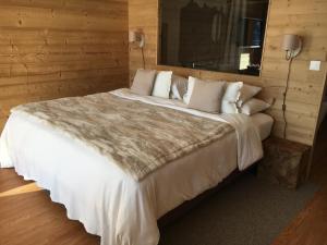 een slaapkamer met een groot bed met witte lakens en kussens bij Appartement supérieur Winoka Lodge in Veysonnaz