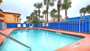 una piscina con palmeras y una valla azul en Best Western Oceanfront, en Jacksonville Beach
