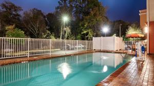 a swimming pool at night with a fence and lights at Best Western Plus Jacksonville West in Jacksonville