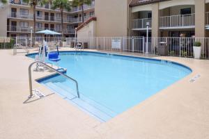a large swimming pool with a chair and an umbrella at Best Western International Drive - Orlando in Orlando