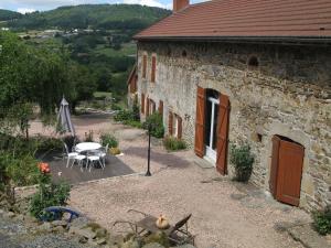 - un bâtiment en pierre avec une table et des chaises devant dans l'établissement Le Peyroux, à Teilhet