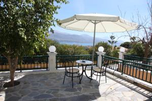 een patio met een tafel en stoelen en een parasol bij Villa Elena in Lixouri