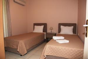 2 Betten in einem kleinen Zimmer mit einem Nachttisch in der Unterkunft Villa Elena in Lixouri