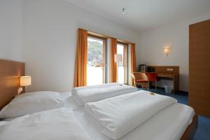 two beds in a hotel room with a desk and a window at Hotel Garni Sunshine in Sölden