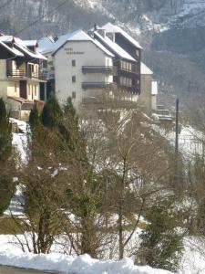 a building on a snowy hill with trees in front at La Cascade in Mouthier-Haute-Pierre